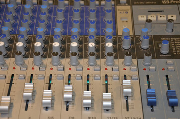 Professional audio mixing console with faders and adjusting knobs,