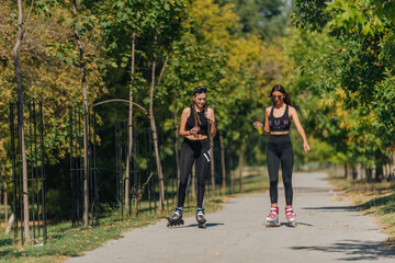 Fototapeta premium Sporty girls roller skating in park on inline skates. Female bonding.