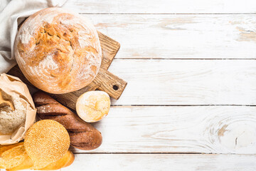 Fototapeta premium Assortment fresh bread and buns at white kitchen table.
