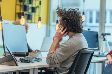 Obraz premium Handsome bearded guy with afro haircut working with his coworkers at a startup company.
