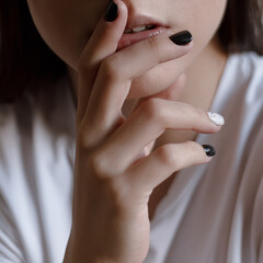 Woman's hand with black and white manicure touching chin emotion thinking close up
