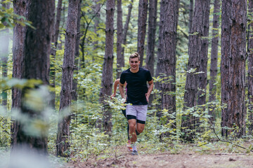 Obraz premium Strong male runner jogging for marathon on forest road