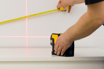 the specialist uses an electronic laser to check right angles and lines while taking measurements...