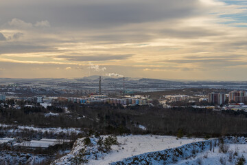 Winter view of the city of Brno in the Czech Republic in Europe. Houses and chimneys are visible. Palava can be seen in the background. There are dramatic clouds in the sky. Photo from Hady quarry.