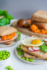 Healthy sandwiches or burgers with whole grains bread, microgreens, egg, fresh vegetables Ketogenic diet, intermittent fasting, weight loss. Breakfast and dieting time concept. White table, copy space