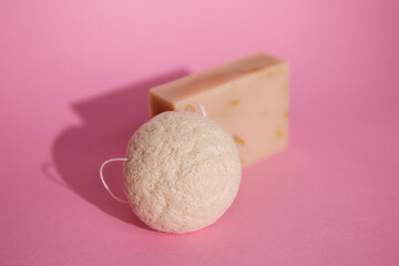 Natural cosmetics on pink background. Flat lay top view skin care products branding mock up. Natural konjac sponge and natural hand made soap. Healthy lifestyle, zero waste cosmetic routine. 