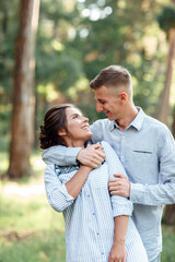 Cheerful young woman and man are hugging outdoors in summer park. Dating and romantic vacation. couple in love gently looking at each other on sunny day. Love and relationships between young people