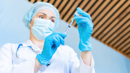 A doctor wearing a protective medical mask prepares to inject with the coronavirus vaccine. The concept of home treatment, calling doctor at home.