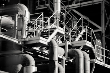 Tubos, pasarelas de metal y tuberías de una fábrica. Espacio industrial en blanco y negro con...