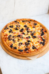 Pizza with mozzarella cheese, ham, mushrooms, chicken and sauce on gray background
