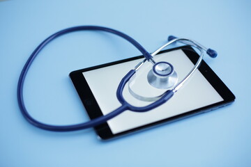 Fototapeta na wymiar Blue medical stethoscope and tablet on blue background