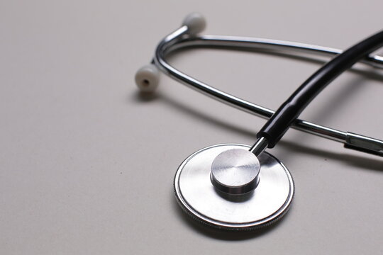Black medical stethoscope on gray background