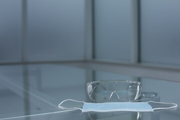 Safety goggles and face shield on glass table