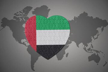 puzzle heart with the national flag of united arab emirates on a world map background.