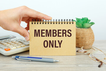 MEMBERS ONLY is written on a notepad on office desk
