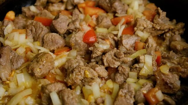fried pork meat with tomatoes and onions on pan