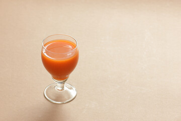 Carrot orange juice in a vintage glass on brown background, closeup, copy space, monochrome food and drink concept