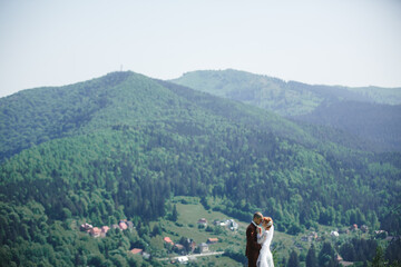 happy stylish bride and groom running and having fun in mountains on summer sunny day. gorgeous newlywed couple laughing, true feelings. emotional romantic moment.