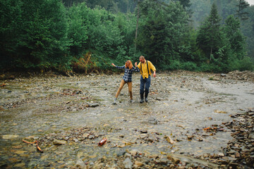 Playful happy handsome couple having while walking in woods. tourists in the mountains. Adventure in nature concept. couple in the mountains