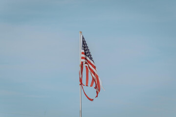 Damaged torn down American flag pole under a perfectly clear sky