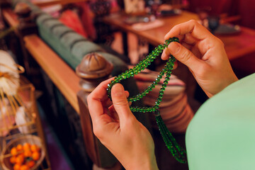 Concentrated woman praying wearing rosary beads. Namaste. Close up hands.