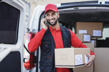 Caucasian courier man call clients with smartphone while holding delivery box out of van transportation © Sabrina