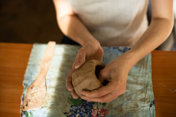 Pottery. A girl with a string in her hands cuts the top layer off clod clay. The process of modeling ceramic ware.