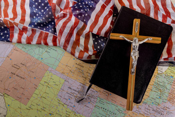 Holy Bible on of the Christian cross the hope of mankind for salvation on way to God through prayer on American flag and U.S. map