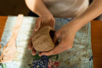 Pottery. A girl with a string in her hands cuts the top layer off clod clay. The process of modeling ceramic ware.