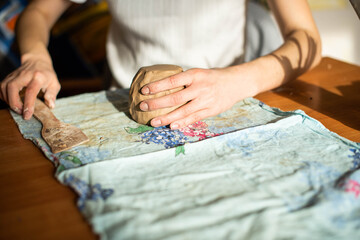 Pottery. A girl with a string in her hands cuts the top layer off clod clay. The process of modeling ceramic ware.