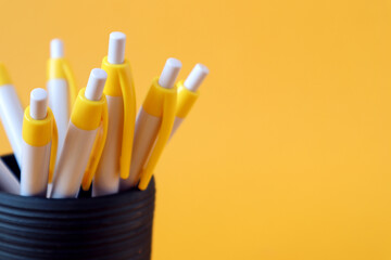 Fountain pens in a cup on a yellow background, close-up, space for text