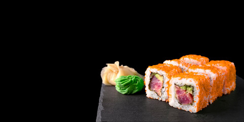 California Tuna Roll In Orange Tobiko Roe Isolated On Black Background. Japanese Cuisine Sushi Set With Tuna And Avocado On Grey Black Plate Copy Space Wide Large Banner.