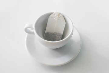 Tea bag in empty glass mug on white background