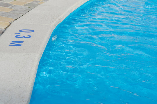 close up image of sign of depth in meters in swimming pool, shallow pool for children with blue water, no people around,  safety on water