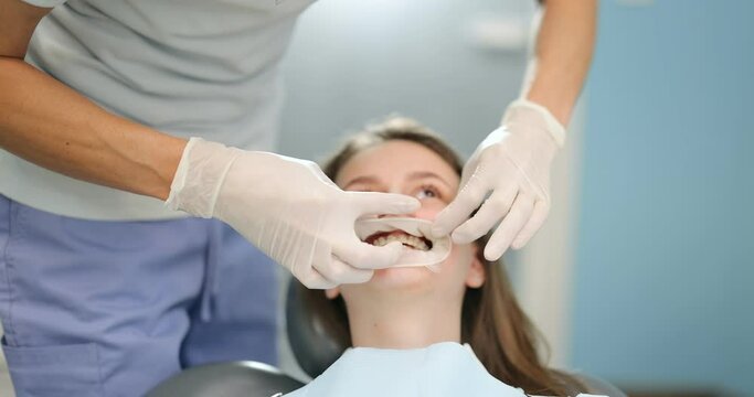 Young dentist wearing optragate for the young patient, preparing for the dental checkup. Regular visit to the orthodontist