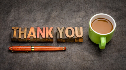 thank you web banner - word abstract in vintage letterpress wood type blocks  with a cup of coffee against black textured bark paper