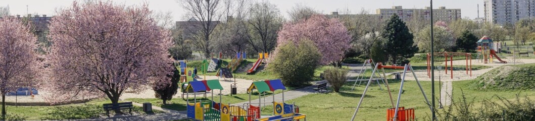 panorama miejskiego placu zabaw, pusty plac zabaw z powodu zakazów epidemicznych, wiosna w mieście z kwitnącym krzewami