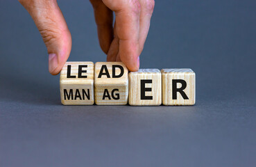 Manager versus leader symbol. Businessman flips wooden cubes and changes the word 'manager' to...