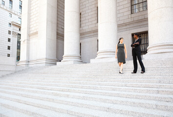 Two women in discussion on the exterior steps of a courthouse. Could be lawyers, business people etc.