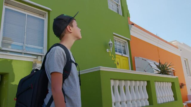 Boy tourist in Cape town Bo-Kaap Malay area, perspective of cobble stone street, colored terrace houses, laundry on line side of house.