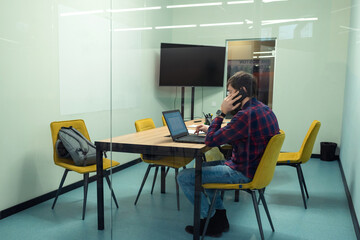 A young man works in the office at the computer. Co-working, Business and entrepreneurship concept. Side view