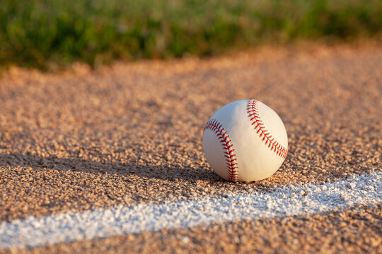 Low angle selective focus view of a baseball on a basepath with white stripe
