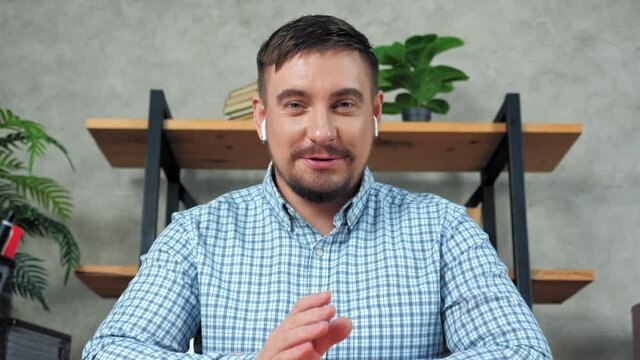 Webcam view smiling bearded businessman wears wireless earphones looks laptop camera tells company employees remote online video conference call chat computer, distance business meeting in home office