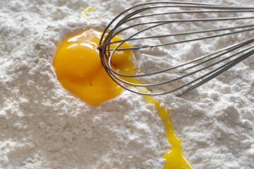 Egg, flour, whisk in the kitchen close-up. Baking ingredients. Cooking concept, top view