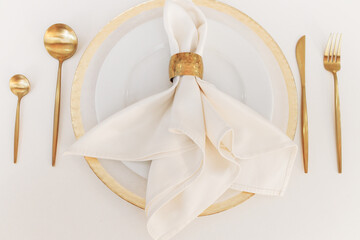 beautiful wedding tableware lies on a white table. gold spoons and forks. wedding decorations. banquet table. empty plate