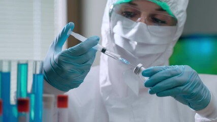Close-up of concentrated female virologist worker in protective coverall holding sterile syringe with transparent solution and mixing it with light yellow powder in vial for creating difficult - Powered by Adobe