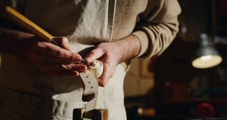 Cinematic shot of experienced master artisan luthier painstaking detail work on fine quality wood violin in creative workshop.Concept of spiritual instrument,handmade, art, orchestra, artisan, passion