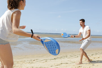 a happy couple is playing beach tennis