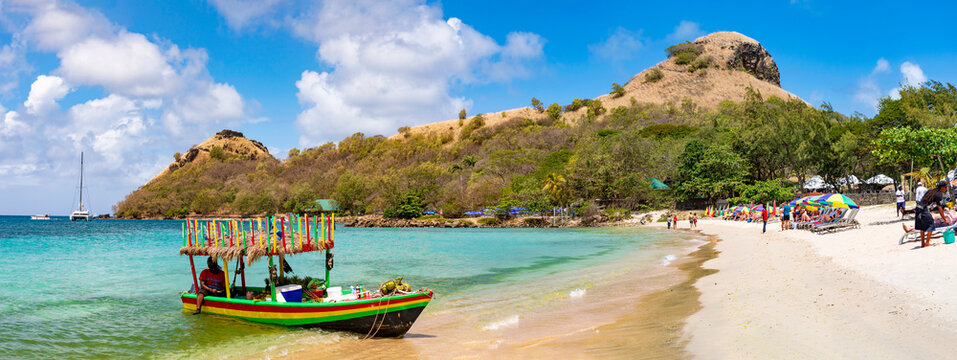 Strand von Pigeon Island auf der Insel St. Lucia. Eine tropische Insel mit Sandstrand, blauer Himmel und ein Boot im Vordergrund, Panorama.