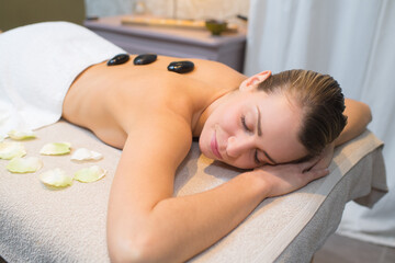 Obraz na płótnie Canvas woman relaxing in spa salon with hot stones on body